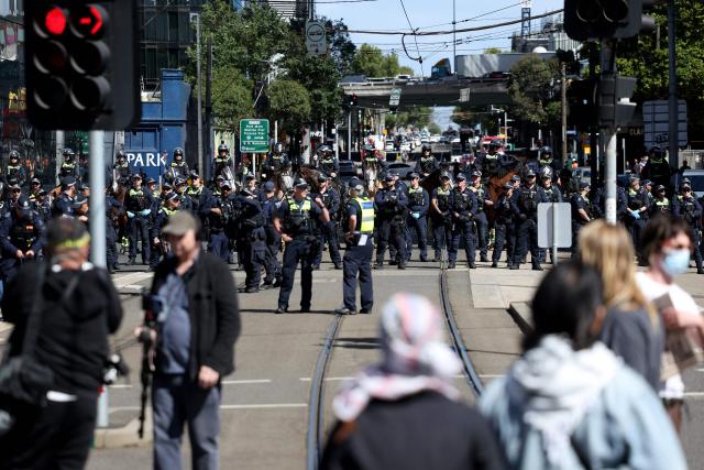 Protesters stand in front of police officers as they cordon off an intersection during the visit of Israel’s President Isaac Herzog in Melbourne on February 12, 2026. Herzog's tightly secured, four-day trip aims to console Australia's Jewish community after the December shooting at Sydney's Bondi Beach that killed 15 people at a Hanukkah festival. (Photo by MARTIN KEEP / AFP)