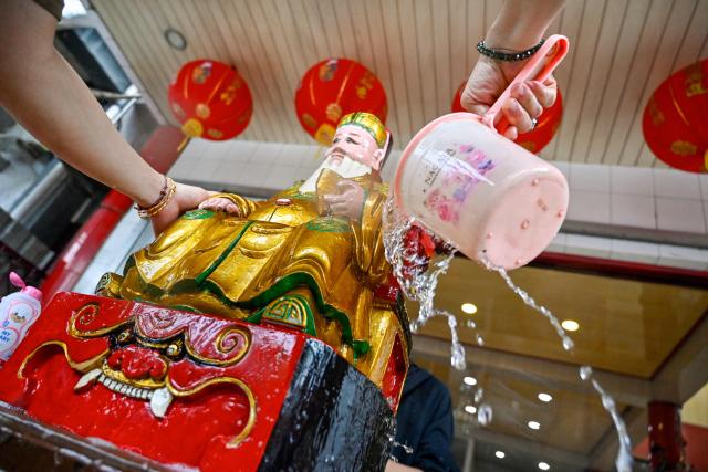 A volunteer washes a deity statue at the Dharma Bakti Temple in Banda Aceh, Indonesia's Aceh province on February 12, 2026, in preparation for the upcoming Lunar New Year of the Horse. (Photo by CHAIDEER MAHYUDDIN / AFP)
