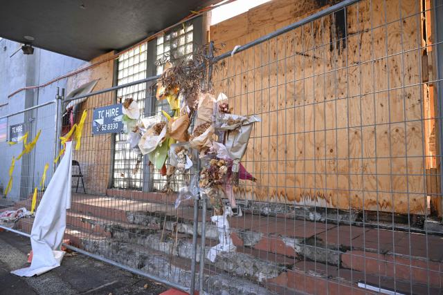 Banners and flowers hang from a security fence outside the torched Adass Israel Synagogue in Melbourne on February 12, 2026. Israel’s President Isaac Herzog was scheduled to visit the synagogue during his visit to Melbourne, but the event was cancelled. Herzog's tightly secured, four-day trip aims to console Australia's Jewish community after the December shooting at Sydney's Bondi Beach that killed 15 people at a Hanukkah festival. (Photo by WILLIAM WEST / AFP)