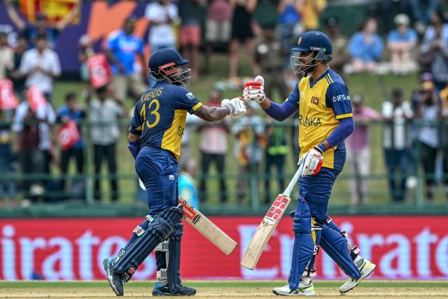 Sri Lanka's captain Dasun Shanaka (R) and his teammate Kusal Mendis bump their fists during the 2026 ICC Men's T20 Cricket World Cup group stage match between Sri Lanka and Oman at the Pallekele International Cricket Stadium in Kandy on February 12, 2026. (Photo by Ishara S. KODIKARA / AFP)
