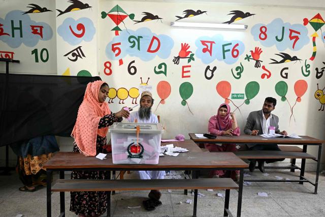 A woman (L) casts her ballot at a polling station during Bangladesh's general election in Dhaka on February 12, 2026. (Photo by Sajjad HUSSAIN / AFP)