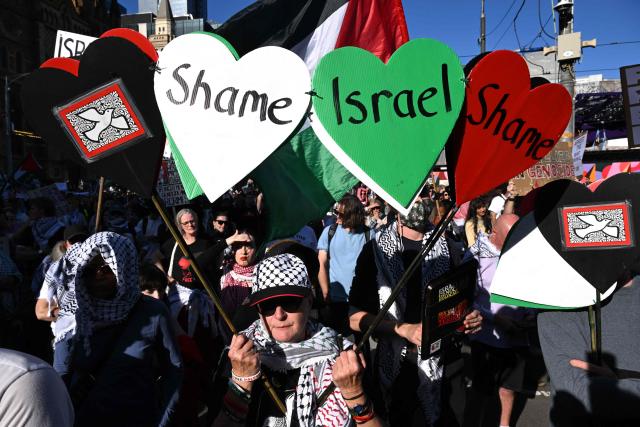Protesters hold placards and flags outside Flinders Street station during the visit of Israel’s President Isaac Herzog in Melbourne on February 12, 2026. Herzog's tightly secured, four-day trip aims to console Australia's Jewish community after the December shooting at Sydney's Bondi Beach that killed 15 people at a Hanukkah festival. (Photo by WILLIAM WEST / AFP)