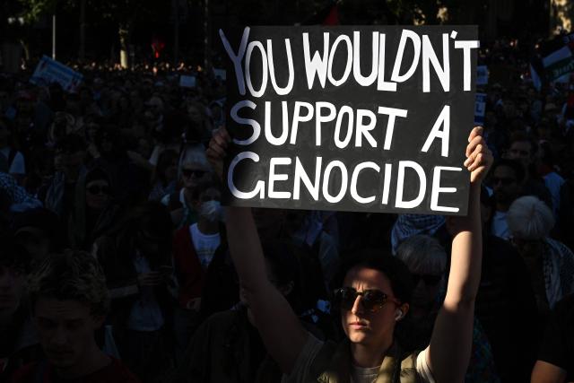 A protester holds a placard outside Flinders Street station during the visit of Israel’s President Isaac Herzog in Melbourne on February 12, 2026. Herzog's tightly secured, four-day trip aims to console Australia's Jewish community after the December shooting at Sydney's Bondi Beach that killed 15 people at a Hanukkah festival. (Photo by WILLIAM WEST / AFP)
