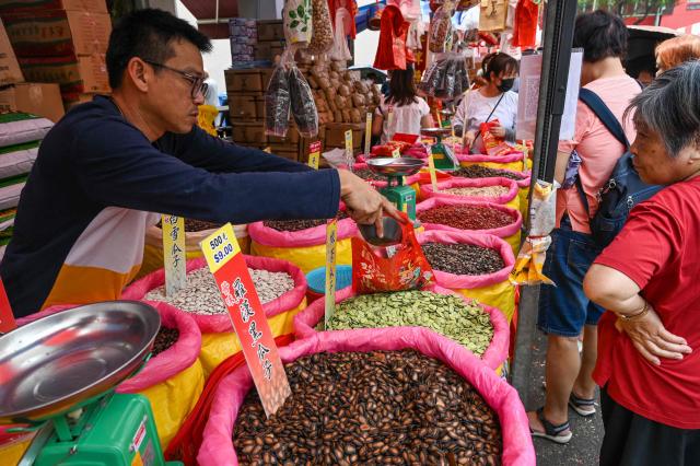 A vendor fills a bag of dried snacks at a stall ahead of the upcoming Lunar New Year in the Chinatown district of Singapore on February 12, 2026. (Photo by Roslan RAHMAN / AFP)