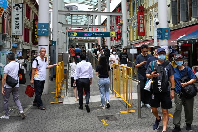 People walk along the street next to the Chinatown MRT station in the Chinatown district of Singapore on February 12, 2026. (Photo by Roslan RAHMAN / AFP)