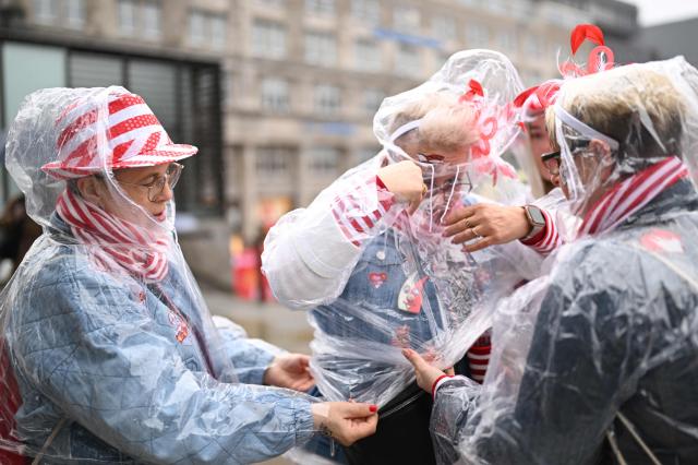 Revellers prepare with ponchos against rain as they arrive for the start of the carnival season during the Women's Carnival Day in Cologne, western Germany on February 12, 2024. The festivities begin with "Weiberfastnacht", a raucous street party in which women snip off men's ties. (Photo by INA FASSBENDER / AFP)