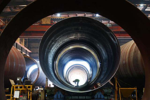 (FILES) An employee works in a factory which produces wind turbine towers to be exported overseas, in Lianyungang, in China’s eastern Jiangsu province on July 29, 2025. China's emissions of planet-warming carbon dioxide likely fell last year, analysis showed on February 12, 2026, raising hopes the world's biggest emitter might be nearing a peak, but continued coal growth means progress is fragile. (Photo by AFP) / China OUT