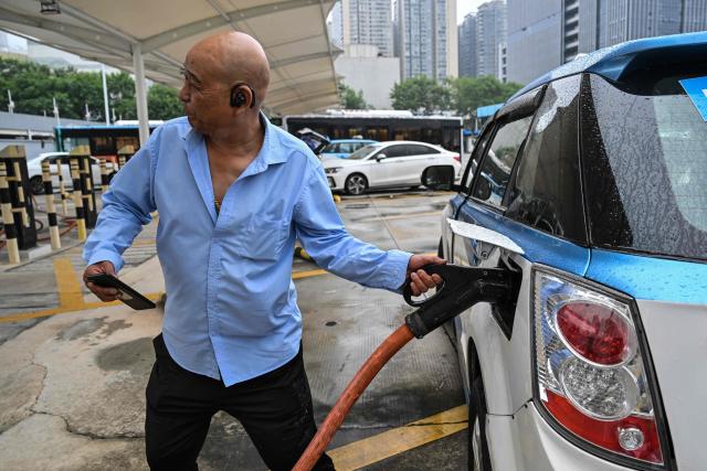 (FILES) In this picture taken on October 18, 2023, a taxi driver charges his electric vehicle at Antuoshan charging station in Shenzhen, China's southern Guangdong province. China's emissions of planet-warming carbon dioxide likely fell last year, analysis showed on February 12, 2026, raising hopes the world's biggest emitter might be nearing a peak, but continued coal growth means progress is fragile. (Photo by Hector RETAMAL / AFP)