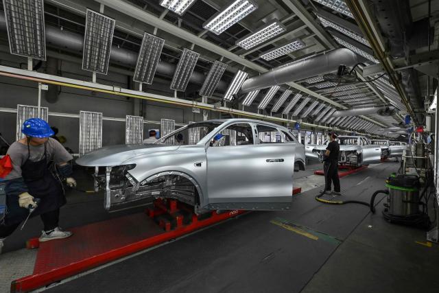 (FILES) Employees work on an electric vehicle (EV) production line at the Leapmotor factory in Jinhua, China's eastern Zhejiang province on September 18, 2024. China's emissions of planet-warming carbon dioxide likely fell last year, analysis showed on February 12, 2026, raising hopes the world's biggest emitter might be nearing a peak, but continued coal growth means progress is fragile. (Photo by Adek BERRY / AFP)