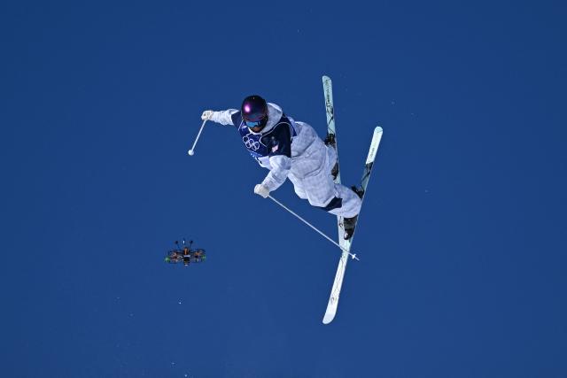 A broadcast drone hovers next to Britain's Mateo Jeannesson as he competes in the freestyle skiing men's moguls qualification 2 during the Milano Cortina 2026 Winter Olympic Games at Livigno Aerials & Moguls Park, in Livigno (Valtellina), on February 12, 2026. (Photo by Kirill KUDRYAVTSEV / AFP)