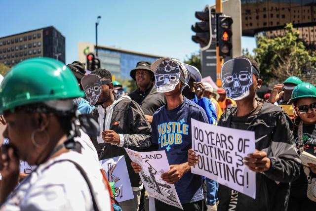 Members of South Africa's mining affected communities react while wearing face masks during their protest outside Anglo American's headquarters in Johannesburg on February 12, 2026. Protesters are demanding full accountability before Anglo American exits South Africa, including rehabilitation, outstanding social obligations and transparency on liabilities. (Photo by Phill Magakoe / AFP)