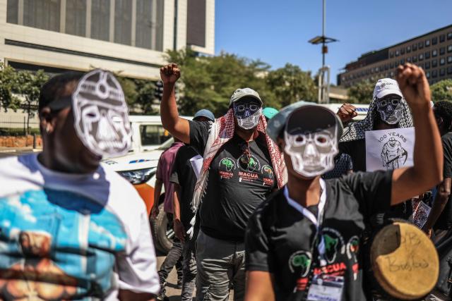 Members of South Africa's mining affected communities react while wearing face masks during their protest outside Anglo American's headquarters in Johannesburg on February 12, 2026. Protesters are demanding full accountability before Anglo American exits South Africa, including rehabilitation, outstanding social obligations and transparency on liabilities. (Photo by Phill Magakoe / AFP)