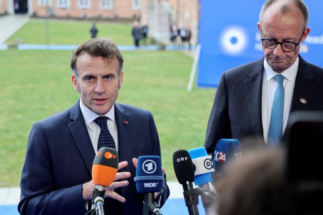 France's President Emmanuel Macron (L) and Germany's Chancellor Friedrich Merz speak to the press upon their arrival to take part in the Informal EU Leaders' Retreat at the Alden Biesen Castle in Alden Biesen, central Belgium on February 12, 2026. (Photo by Ludovic MARIN / AFP)