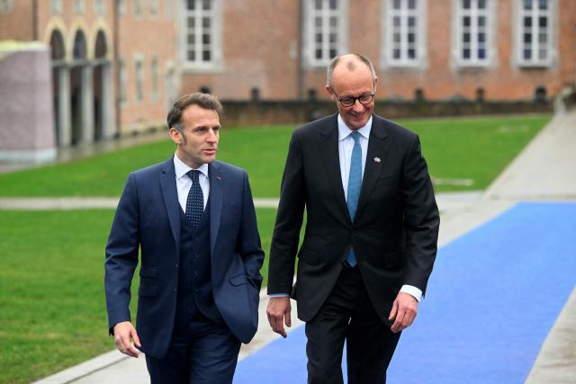 France's President Emmanuel Macron (L) and Germany's Chancellor Friedrich Merz arrive to attend the Informal EU Leaders' Retreat at the Alden Biesen Castle in Alden Biesen, central Belgium on February 12, 2026. (Photo by NICOLAS TUCAT / AFP)