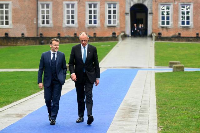 France's President Emmanuel Macron (L) and Germany's Chancellor Friedrich Merz arrive to attend the Informal EU Leaders' Retreat at the Alden Biesen Castle in Alden Biesen, central Belgium on February 12, 2026. (Photo by NICOLAS TUCAT / AFP)