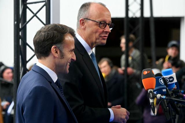 France's President Emmanuel Macron (L) and Germany's Chancellor Friedrich Merz speak to the press as they arrive to attend the Informal EU Leaders' Retreat at the Alden Biesen Castle in Alden Biesen, central Belgium on February 12, 2026. (Photo by NICOLAS TUCAT / AFP)