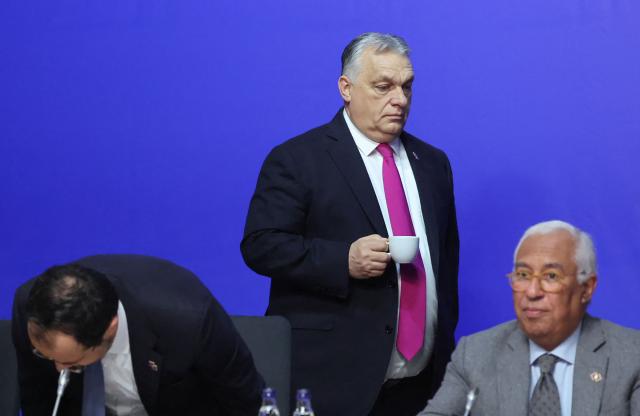 Hungary's Prime Minister Viktor Orban (C) carries a beverage as he walks past European Council President Antonio Costa (R) during the Informal EU Leaders' Retreat at the Alden Biesen Castle in Alden Biesen, central Belgium on February 12, 2026. (Photo by Ludovic MARIN / AFP)