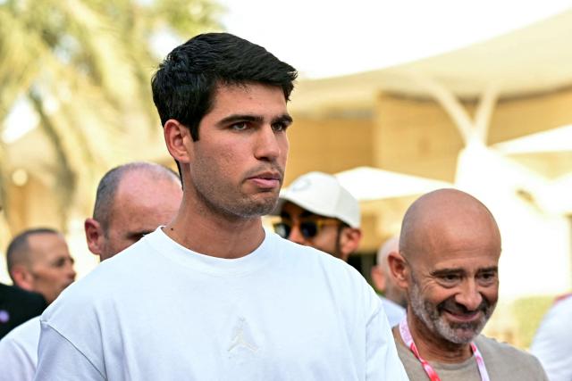 Spain's tennis player Carlos Alcaraz (L) visits the track on the second day of the Formula One pre-season testing at the Bahrain International Circuit in Sakhir on February 12, 2026. (Photo by Giuseppe CACACE / AFP)