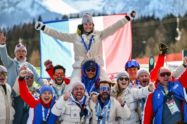 France's silver medalist Romane Miradoli celebrates with Team France members after the podium of the women's super-G event during the Milano Cortina 2026 Winter Olympic Games at the Tofane Alpine Skiing Centre in Cortina d’Ampezzo on February 12, 2026. (Photo by Marco BERTORELLO / AFP)