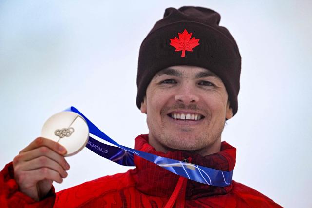 Silver medallist Canada's Mikael Kingsbury celebrates on the podium after the freestyle skiing men's moguls final during the Milano Cortina 2026 Winter Olympic Games at Livigno Aerials & Moguls Park, in Livigno (Valtellina), on February 12, 2026. (Photo by Kirill KUDRYAVTSEV / AFP)
