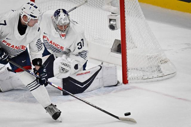 France's #07 Pierre Crinon (L) controls the puck in front of France's #30 Antoine Keller during the men's preliminary round Group A Ice Hockey match between Switzerland and France at the Milano Santagiulia Ice Hockey Arena during the Milano Cortina 2026 Winter Olympic Games in Milan, on February 12, 2026. (Photo by Alexander NEMENOV / AFP)