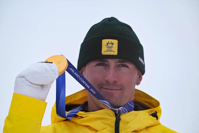 Gold medallist Australia's Cooper Woods celebrates on the podium after the freestyle skiing men's moguls final during the Milano Cortina 2026 Winter Olympic Games at Livigno Aerials & Moguls Park, in Livigno (Valtellina), on February 12, 2026. (Photo by Kirill KUDRYAVTSEV / AFP)