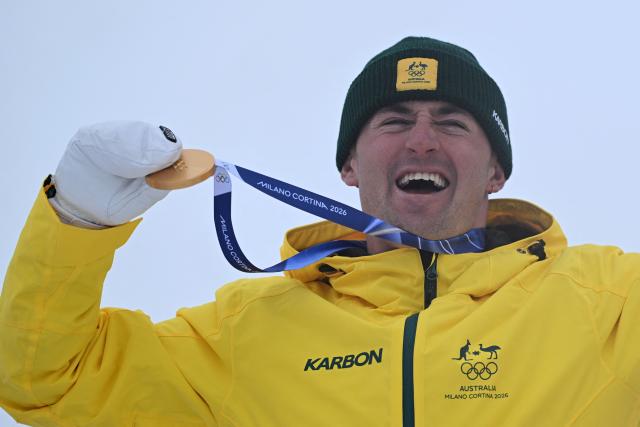 Gold medallist Australia's Cooper Woods celebrates on the podium after the freestyle skiing men's moguls final during the Milano Cortina 2026 Winter Olympic Games at Livigno Aerials & Moguls Park, in Livigno (Valtellina), on February 12, 2026. (Photo by Kirill KUDRYAVTSEV / AFP)