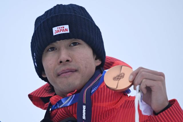 Bronze medallist Japan's Ikuma Horishima celebrates on the podium after the freestyle skiing men's moguls final during the Milano Cortina 2026 Winter Olympic Games at Livigno Aerials & Moguls Park, in Livigno (Valtellina), on February 12, 2026. (Photo by Kirill KUDRYAVTSEV / AFP)