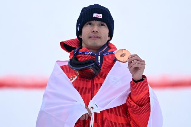 Bronze medallist Japan's Ikuma Horishima celebrates on the podium after the freestyle skiing men's moguls final during the Milano Cortina 2026 Winter Olympic Games at Livigno Aerials & Moguls Park, in Livigno (Valtellina), on February 12, 2026. (Photo by Kirill KUDRYAVTSEV / AFP)