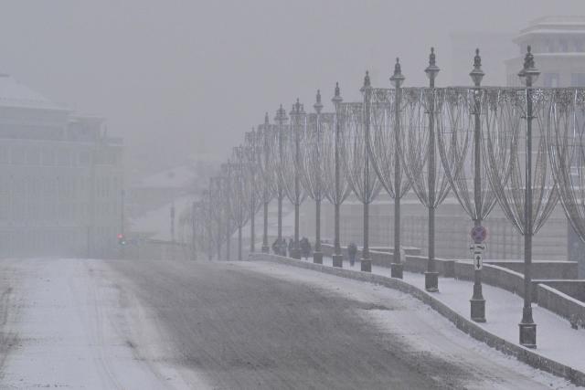 People walk along a bridge over the Moskva river on a snowy day in central Moscow on February 12, 2026. (Photo by Hector RETAMAL / AFP)