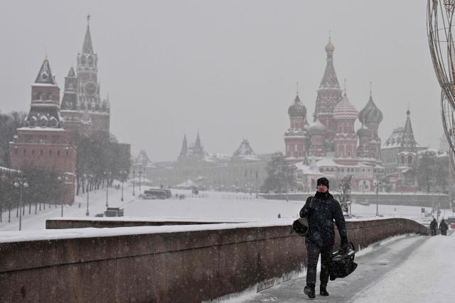 A man walks along a bridge over the Moskva river, with the Kremlin's Spasskaya tower and St. Basil's cathedral seen in distance, during a snowy day in central Moscow on February 12, 2026. (Photo by Hector RETAMAL / AFP)