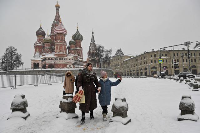People walk near St. Basil's cathedral during a snowy day in central Moscow on February 12, 2026. (Photo by Hector RETAMAL / AFP)