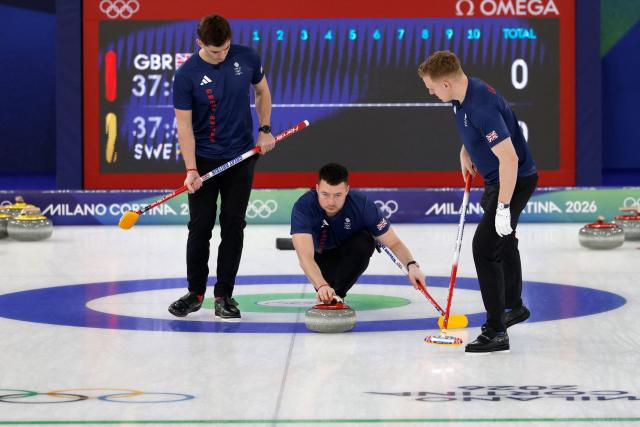Britain's Grant Hardie (L) and Britain's Bobby Lammie (R) watch as Britain's Hammy Mcmillan delivers the stone in the curling men's round robin between Britain and Sweden during the Milano Cortina 2026 Winter Olympic Games at the Cortina Curling Olympic Stadium in Cortina d’Ampezzo on February 12, 2026. (Photo by Odd ANDERSEN / AFP)