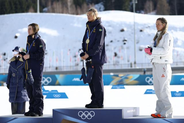 (From L) Silver medallist Sweden's Ebba Andersson, gold medallist Sweden's Frida Karlsson and bronze medallist USA's Jessie Diggins listen to the national anthems on the podium for the women's cross-country skiing 10km interval start free event of the Milano Cortina 2026 Winter Olympic Games at Tesero Cross-Country Skiing Stadium in Lago di Tesero (Val di Fiemme), on February 12, 2026. (Photo by Anne-Christine POUJOULAT / AFP)