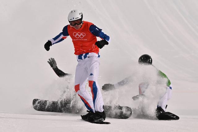 France's Aidan Chollet crosses the finish-line ahead of Austria's Jakob Dusek (back L) and France's Jonas Chollet (back R) in the snowboard men's cross semi final 1 during the Milano Cortina 2026 Winter Olympic Games at Livigno Snow Park, in Livigno (Valtellina), on February 12, 2026. (Photo by Jeff PACHOUD / AFP)