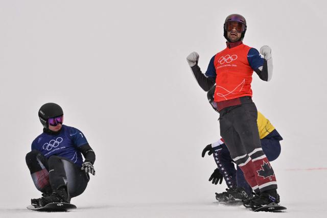 Canada's Eliot Grondin (R) reacts as he crosses the finish-line ahead of Austria's Alessandro Haemmerle (L) and USA's Nick Baumgartner (back R) in the snowboard men's cross semi final 2 during the Milano Cortina 2026 Winter Olympic Games at Livigno Snow Park, in Livigno (Valtellina), on February 12, 2026. (Photo by Jeff PACHOUD / AFP)
