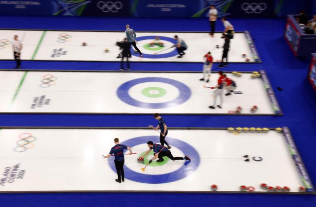 TOPSHOT - Britain's Hammy Mcmillan (front R) delivers the stone during the curling men's round robin between Britain and Sweden during the Milano Cortina 2026 Winter Olympic Games at the Cortina Curling Olympic Stadium in Cortina d’Ampezzo on February 12, 2026, while other teams compete in the background. (Photo by Odd ANDERSEN / AFP)