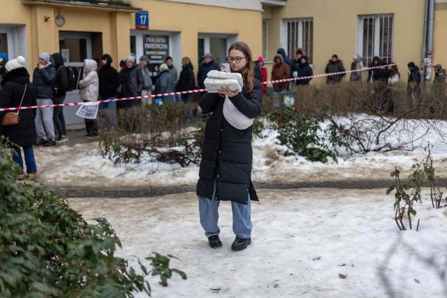 A woman takes pictures of two packages of traditional, marmalade-filled "paczki" - doughnuts, which she just bought after spending over 4 hours queuing in front of one of the most popular and believed to be the oldest "paczki" bakeries in Warsaw to celebrate the end of carnival on February 12, 2026 (Photo by Wojtek RADWANSKI / AFP)