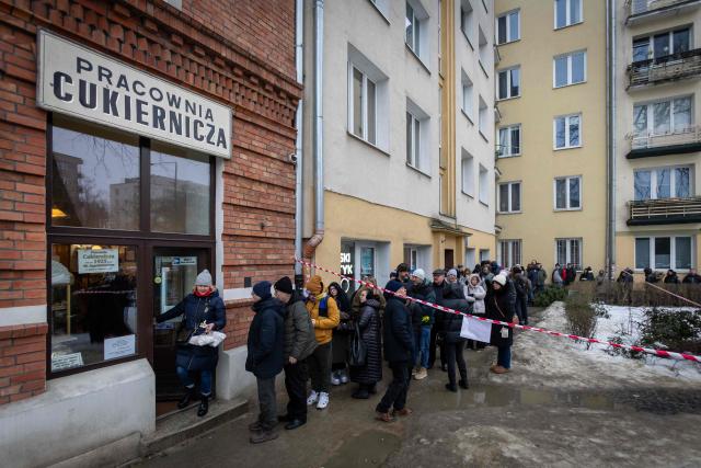 A customer leaves with packages of traditional, marmalade-filled "paczki" - doughnuts,  which she just bought after spending over 4 hours queuing in front of one of the most popular and believed to be the oldest "paczki" bakeries in Warsaw to celebrate the end of carnival on February 12, 2026 (Photo by Wojtek RADWANSKI / AFP)