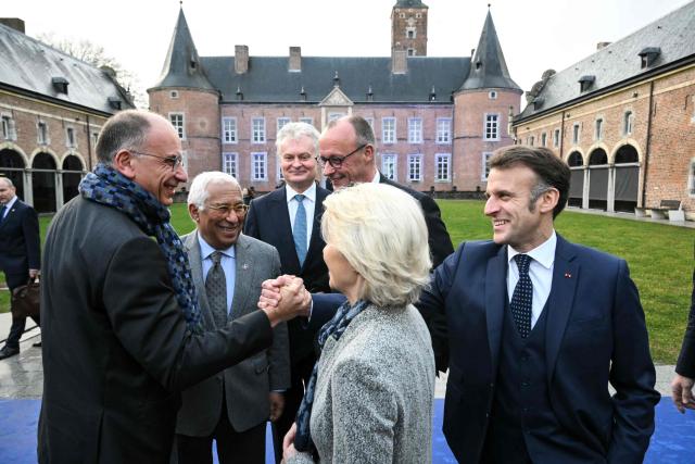 Former Prime Minister of Italy Enrico Letta (L) shakes hands with France's President Emmanuel Macron (R) next to European Council President Antonio Costa (2ndL), Lithuania's President Gitanas Nausedaand (C-L), Germany's Chancellor Friedrich Merz (C-R) and European Commission President Ursula von der Leyen (front) ahead of a working session during the Informal EU Leaders' Retreat at the Alden Biesen Castle, in Rijkhoven on February 12, 2026. (Photo by NICOLAS TUCAT / AFP)