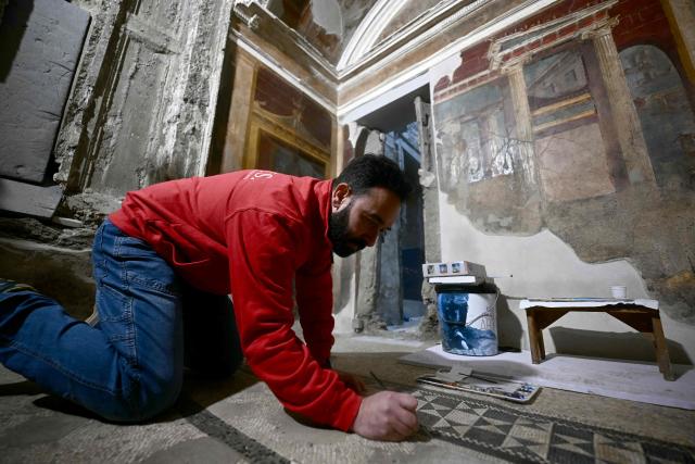 A man works at the restoration of mosaics in the 1st century BC luxurious residence of Poppaea Sabina (Poppea), second wife of the Emperor Nero, in Pompeii on Febuary 12, 2026. The construction site of Poppaea's Villa in Oplontis is about to open its doors for a special guided tour that will allow visitors to discover one of the best-preserved treasures of the Pompeii Archaeological Park, observing firsthand the important excavation and consolidation work underway at the site. (Photo by FILIPPO MONTEFORTE / AFP)