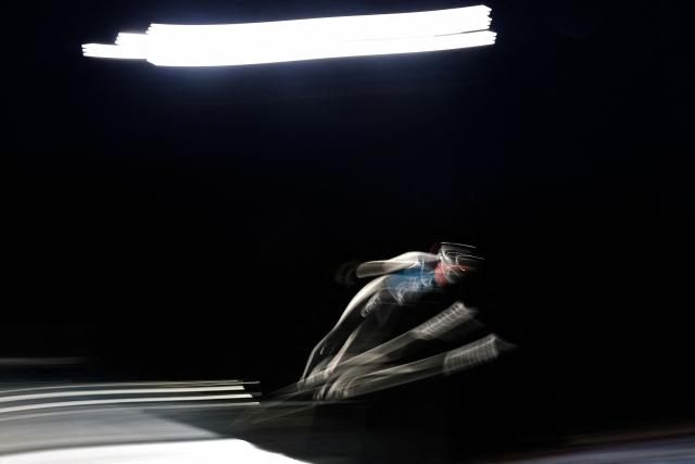 This slow shutter photograph shows an athlete jumping during the women's ski jumping large hill training of the Milano Cortina 2026 Winter Olympic Games at Predazzo Ski Jumping Stadium in Predazzo (Val di Fiemme), on February 12, 2026. (Photo by Anne-Christine POUJOULAT / AFP)