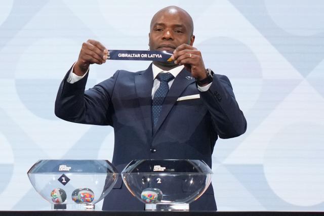 Former Belgium international Mbo Mpenza shows up the paper slip for Gibraltar or Latvia during the 2026/27 UEFA Nations League league phase group D draw ceremony as part of the European football governing body's 50th annual Ordinary Congress in Brussels on February 12, 2026. (Photo by Pau BARRENA / AFP)