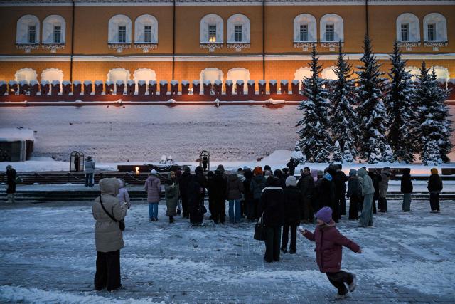 Tourists visit the Eternal Flame and the Tomb of the Unknown Soldier next to the Kremlin wall in the Alexander Garden on a snowy day in central Moscow on February 12, 2026. (Photo by Hector RETAMAL / AFP)