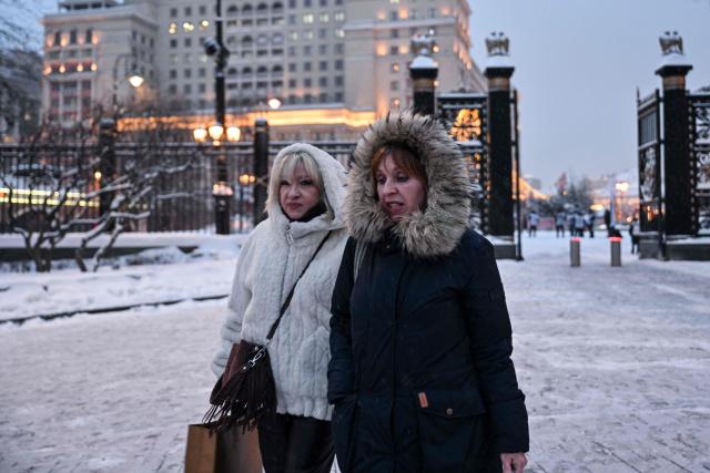 People walk through the Alexander Garden on a snowy day in central Moscow on February 12, 2026. (Photo by Hector RETAMAL / AFP)