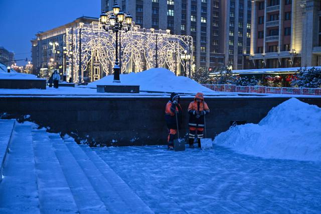 Workers stand in the Alexander Garden in central Moscow on February 12, 2026. (Photo by Hector RETAMAL / AFP)