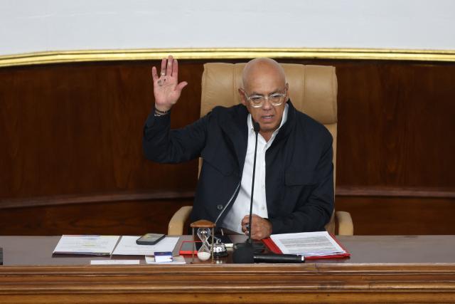 The president of Venezuela's National Assembly Jorge Rodriguez raises his hand as a debate on an amnesty bill proposed by Venezuela's interim president Delcy Rodriguez takes place in Caracas on February 12, 2026. The Venezuelan Parliament began on Thursday the final debate for the approval of a general amnesty law that is expected to lead to the mass release of political prisoners. (Photo by Pedro MATTEY / AFP)