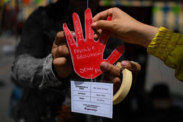 People take part in a demonstration to commemorate the International Day Against the Use of Child Soldiers, also known as Red Hand Day, at Bolivar Square in Bogota on February 12, 2026. (Photo by Luis ACOSTA / AFP)