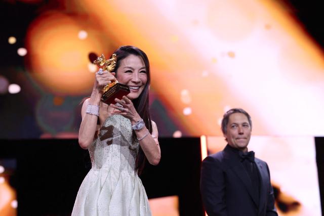 Malaysian actress Michelle Yeoh holds the trophy after being awarded the Honorary Golden Bear from US director Sean Baker (R) during the opening ceremony of the 76th Berlinale, Europe's first major film festival of the year, in Berlin on February 12, 2026. Yeoh is awarded the prize "in recognition of her outstanding achievements in film and cinema". (Photo by Ronny HARTMANN / AFP)