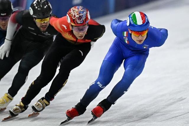 Italy's Pietro Sighel (R), China's Sun Long, Latvia's Roberts Kruzbergs and France's Quentin Fercoq compete in the short track speed skating men's 1000m quarter-final during the Milano Cortina 2026 Winter Olympic Games at Milano Ice Skating Arena in Milan on February 12, 2026. (Photo by Gabriel BOUYS / AFP)